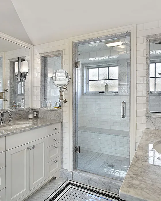 Renovated bathroom finished in marble tile with a frameless glass shower