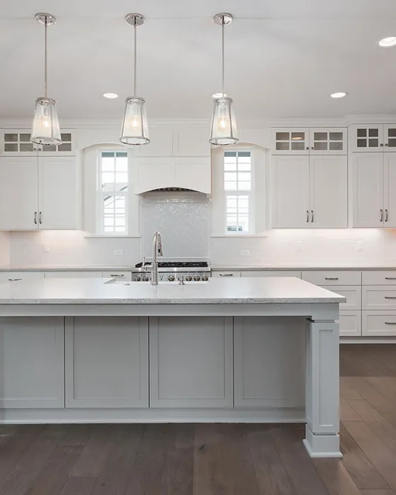 White custom kitchen with a central island, shaker cabinets and recessed lighting